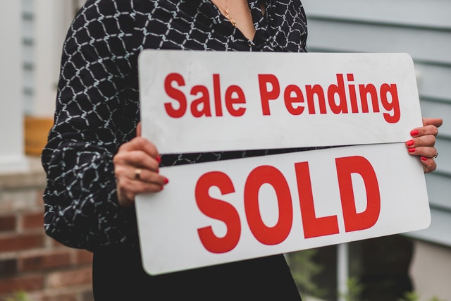 woman holding a sales pending and sold sign